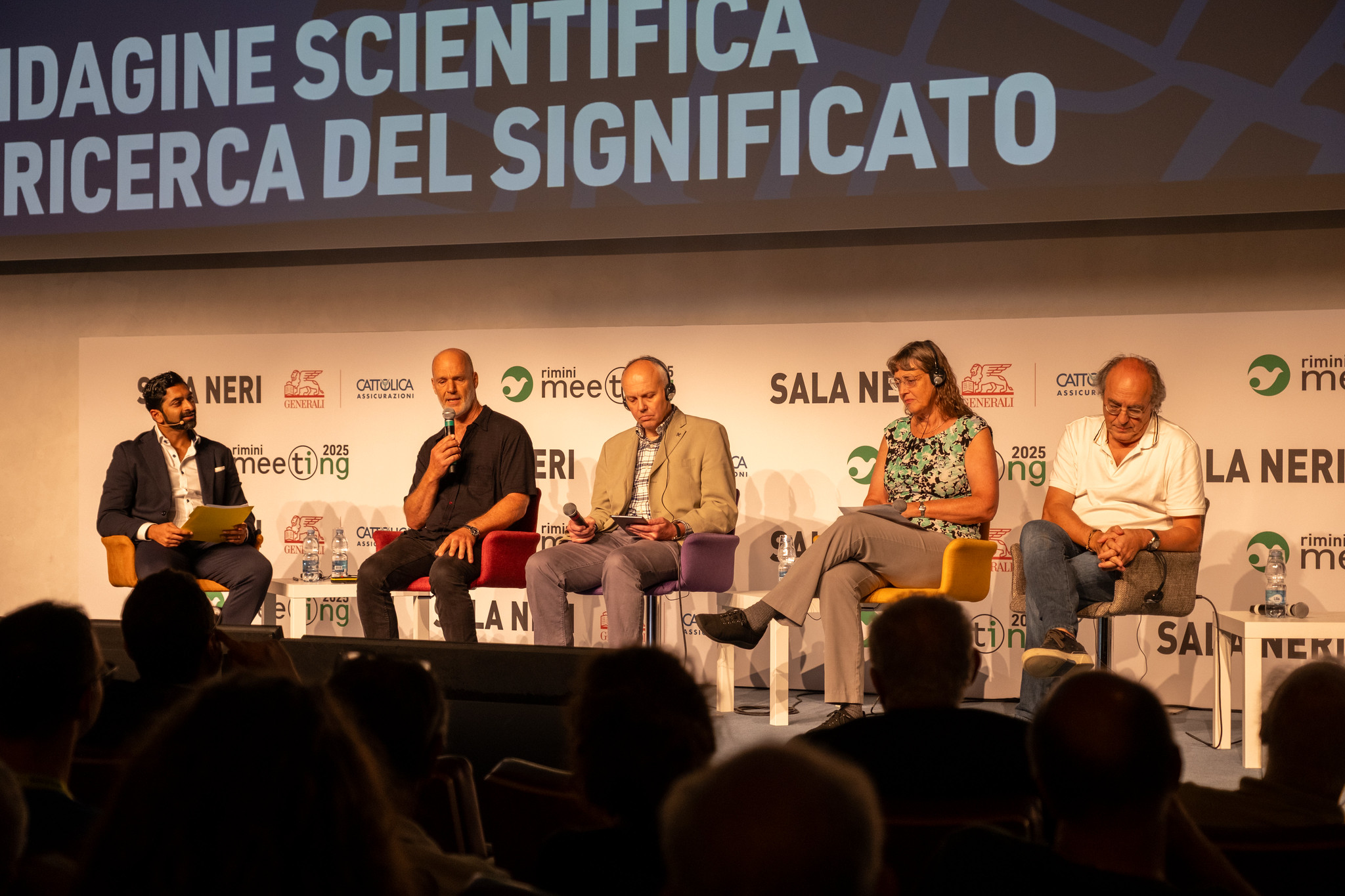 Panelists seated on stage during a science and meaning discussion at the Rimini Meeting